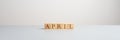 Wide view image of five wooden blocks spelling the word April