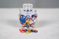 Wide view of a jar of multi colored can pull tabs with some lying loose Royalty Free Stock Photo