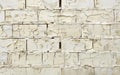 Wide view of an old white brick wall with substantial paint peeling, emphasizing the texture and pattern.