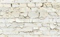 Wide view of an old white brick wall with substantial paint peeling, emphasizing the texture and pattern.