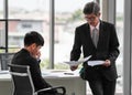 Wide view portrait shot of two Asian businessmen in the office. Senior leader pointing to the paper to show the mistake made by Royalty Free Stock Photo
