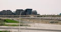 Wide view of subway above ground moves along freeway. Exciting cityscape with subway train going from afar off, cars