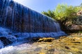 A wide waterfall of clear spring water, in Gan Hashlosha Park