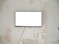 A wide white screen plasma TV in a black frame hangs on an old concrete wall. Royalty Free Stock Photo