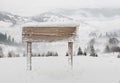 Wide wooden signpost with snow and mountains