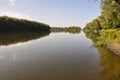 Wide yellow river is slow flowing. Early autumn. Sunny weather and brightgreen trees on the banks fron the both sides