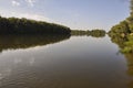 Wide yellow river is slow flowing. Early autumn. Sunny weather and brightgreen trees on the banks fron the both sides