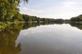 Wide yellow river is slow flowing. Early autumn. Sunny weather and brightgreen trees on the banks fron the both sides