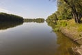 Wide yellow river is slow flowing. Early autumn. Sunny weather and brightgreen trees on the banks fron the both sides