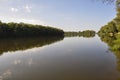 Wide yellow river is slow flowing. Early autumn. Sunny weather and brightgreen trees on the banks fron the both sides