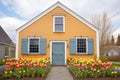 wideangle of saltbox with shutters among spring flowers