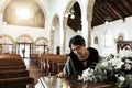 Widow, coffin and sad at a funeral feeling depression from death sitting in a church. Depressed Indian woman with