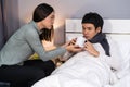 Wife bringing a cup of hot water giving her sick husband drinking on bed at home Royalty Free Stock Photo