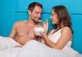 Wife feeding her husband breakfast in bed