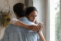 Wife hugging husband keeping secret messaging with lover using cell