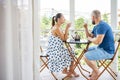 Wife and husband drinking beverage sit on hotel balcony