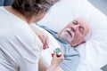 Wife measures the temperature of her sick husband lying in bed Royalty Free Stock Photo