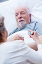 Wife measures the temperature of her sick husband lying in bed Royalty Free Stock Photo