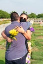 Wife with protective mask trying to comfort her husband in a cemetery. Coronavirus epidemic