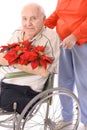Wife pushing handicap man in wheelchair with flowe