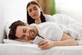 Wife Spying While Cheating Husband Texting On Cellphone In Bedroom Royalty Free Stock Photo