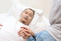 Wife takes and holds hand of her husband who is sick and sleep on bed in hospital, sad emotional moments