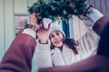 Wife wearing warm hat taking Christmas wreath for decorating house