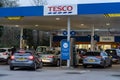 Wigan, UK: March 10, 2022: Queuing cars waiting to buy fuel at a Tesco petrol filling station as British drivers panic