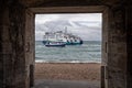 Wightlink ferry en route to the Isle of Wight passing a harbour tour boat, framed through a gate in the ancient harbour ramparts i