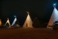 Wigwam Motel units with vehicles outside at night