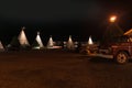Wigwam Motel units with vehicles outside at night