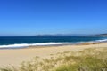 Wild beach with bright sand and vegetation in sand dunes. Blue sea with waves and foam. Sunny day, Galicia, Spain. Royalty Free Stock Photo