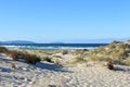 Wild beach with sand dunes and grass. Blue sea with waves and white foam, clear sky, sunny day. Galicia, Spain. Royalty Free Stock Photo