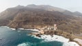 Wild black sand beach with cave and small boats and a port with lighthouse in volcano coastline. Volcanic soil in rural village in Royalty Free Stock Photo