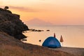 Wild camping on the beach in sunset. Beautiful orange sky and clear calm sea water in the background Royalty Free Stock Photo