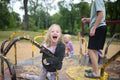 Wild Child Smiling and Screaming as She Rides Merry-go-Round at Playground