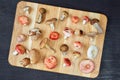 Wild edible various mushrooms on the wooden brown board on the dark background