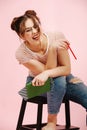 Wild emotional girl sitting on a stool with pen and notebook, tilting to side