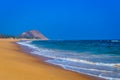 Wild Empty Tropical beach, vibrant yellow sand, bright blue sky, crystal clear waters with water crashing on the shore at daytime Royalty Free Stock Photo