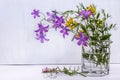 Wild field flowers in a glass of water on white background