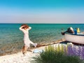 Wild flowers on beach sand fish boat on horizon women in white dress and straw hat blue sky and green sea water tropical landscape Royalty Free Stock Photo