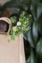 Wild flowers bouquet in canvas textile bag, natural summer background. Greeting card, seasons, vacation concept