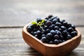 Wild forest bilberries with green leaves inside a bowl on brown wooden background Royalty Free Stock Photo