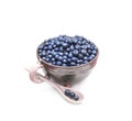 Wild forest blueberries in the clay pot with spoon isolated on white background