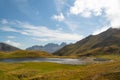 Wild horses drinking water in a mountain lake surrounded by grasslands in the Pyrenees at sunset