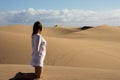 The woman on her knees observes the great desert dunes. Royalty Free Stock Photo