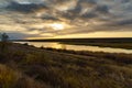 Wild natural landscape at sunset, golden color with dark silhouettes, late autumn, lake, dry grass, bare branches of trees without Royalty Free Stock Photo