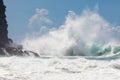 Wild, powerful wave splashing, crashing on rocky shore, under bl