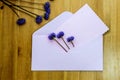 Wild purple flowers with pink envelop on wooden background. Flat lay. Top view.