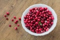 Wild and ripe cranberry in white plate on brown wooden background Royalty Free Stock Photo